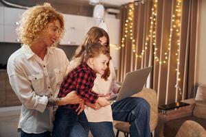 Spending weekend together. Happy family of mother, daughter and son is on the kitchen at evening time photo