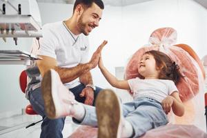 Job well done. Little girl visiting dentist in clinic. Conception of stomatology photo