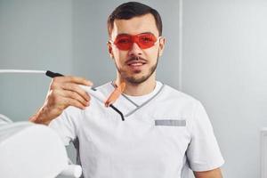 Portrait of professional dentist with equipment that standing indoors photo