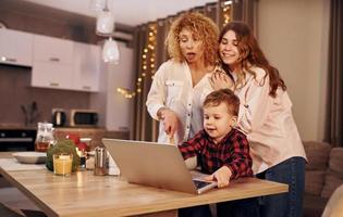 Cheerful people having happy weekend. Family of mother, daughter and son is on the kitchen at evening time photo