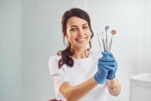 Portrait of professional female dentist with equipment that standing indoors photo