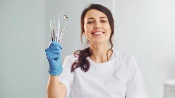 Portrait of professional female dentist with equipment that standing indoors photo