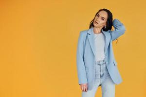 sobre fondo amarillo. mujer europea en ropa elegante de moda está posando en el interior foto