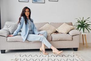 en casa con chaqueta azul. mujer europea en ropa elegante de moda está posando en el interior foto