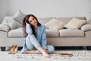 en casa con chaqueta azul. mujer europea en ropa elegante de moda está posando en el interior foto