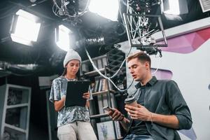 Young man is preparing for TV online broadcast. Woman helps with make up photo