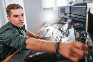 Setting the equipment. Young man is indoors in the radio studio is busy by broadcast photo