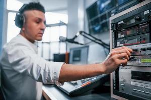 Setting the equipment. Young man is indoors in the radio studio is busy by broadcast photo