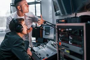 Conception of teamwork. Two guys is indoors in the radio studio is busy by broadcast photo