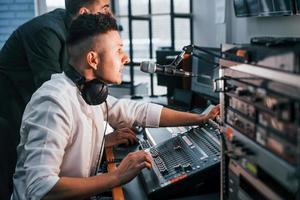 Conception of teamwork. Two guys is indoors in the radio studio is busy by broadcast photo