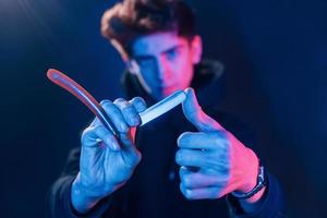 Young barber with work equipment standing in the studio with neon lighting photo