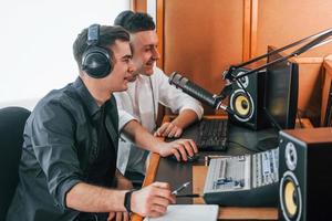 Two guys is indoors in the radio studio is busy by broadcast photo