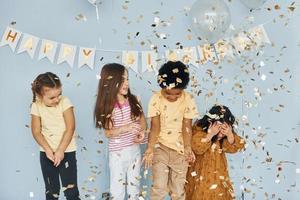 Balloons and confetti. Children on celebrating birthday party indoors have fun together photo