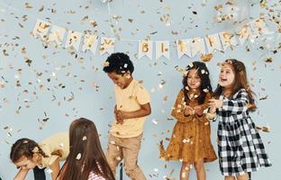 Balloons and confetti. Children on celebrating birthday party indoors have fun together photo