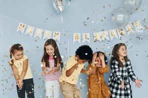 Balloons and confetti. Children on celebrating birthday party indoors have fun together photo