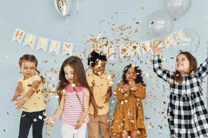 Balloons and confetti. Children on celebrating birthday party indoors have fun together photo