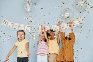 Balloons and confetti. Children on celebrating birthday party indoors have fun together photo