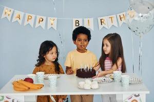 Holiday cake. Children on celebrating birthday party indoors have fun together photo