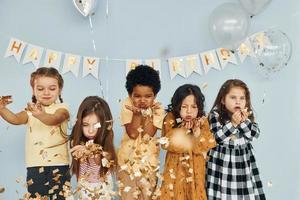 globos y confeti. los niños que celebran la fiesta de cumpleaños en el interior se divierten juntos foto