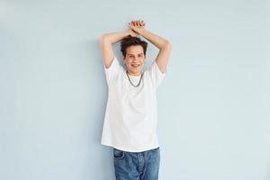 Young gay man is standing in the studio and posing for a camera photo