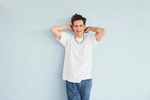 Young gay man is standing in the studio and posing for a camera photo