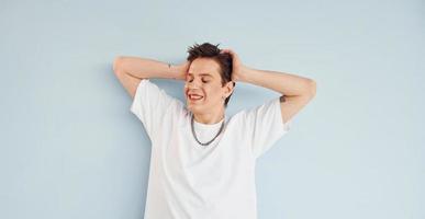 Young gay man is standing in the studio and posing for a camera photo