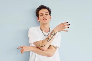 Young gay man is standing in the studio and posing for a camera. Red colored lips photo