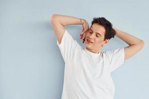 Young gay man is standing in the studio and posing for a camera photo