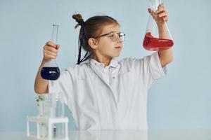 Little girl in coat playing a scientist in lab by using equipment photo