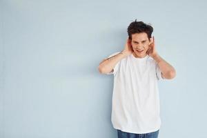 Young gay man is standing in the studio and posing for a camera photo