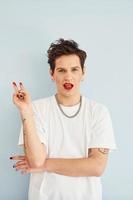 Young gay man is standing in the studio and posing for a camera. Lips in red lipstick photo