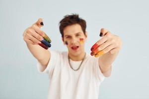 Young gay man is standing in the studio and posing for a camera. Shows gestures photo