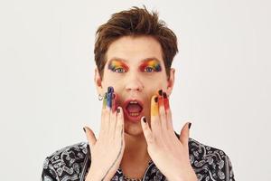 Young gay man is standing in the studio and posing for a camera. Gesturing and doing facial expressions photo