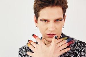 Young gay man is standing in the studio and posing for a camera. Gesturing and doing facial expressions photo