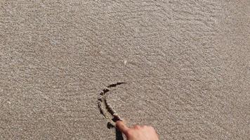 dessinant un coeur dans le sable et effacé par les vagues de la mer video