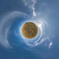 green tiny planet in blue sky with beautiful clouds with transformation of spherical panorama 360 degrees. Curvature of space. photo