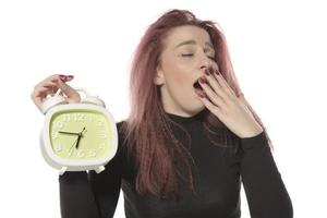 worried young woman holding alarm clock in her hand photo