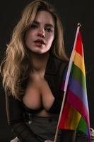 mujer lesbiana sosteniendo la bandera del arco iris aislada sobre fondo negro. símbolo internacional lgbt de la comunidad lesbiana, gay, bisexual y transgénero. foto