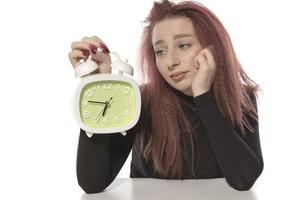mujer joven preocupada que sostiene el despertador en su mano foto