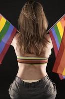 mujer lesbiana sosteniendo la bandera del arco iris aislada sobre fondo negro. símbolo internacional lgbt de la comunidad lesbiana, gay, bisexual y transgénero. foto