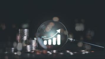 Stack of coins and a magnifying glass on the table,icon representation of success and profit,concept of progress in development financial performance and investment,Fund growth and savings photo