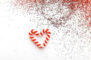 composición navideña con bastones de caramelo en forma de oh corazón sobre fondo de madera azul con lentejuelas rojas foto