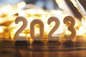 wooden number 2023 onchristmas beautifull shiny gold background. sparkle festive blurred bokeh photo