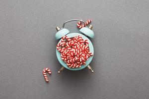 Christmas background with candy canes on alarm clock on gray background photo