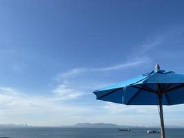 sombrilla de playa azul sobre fondo de cielo azul de verano foto