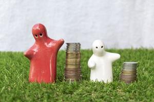 maqueta de estatua familiar y pila de monedas en el suelo de hierba con fondo blanco foto