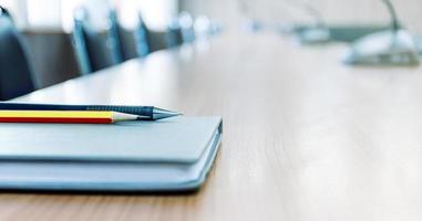 Pencil and notebook on table in meeting room with copy space photo