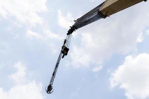 Yellow crane boom with hooks and blue sky background photo