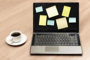 Colorful memo sticker on display laptop with black coffee cup on table photo