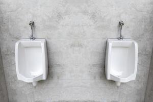 Two white porcelain urinals with gray loft wall photo